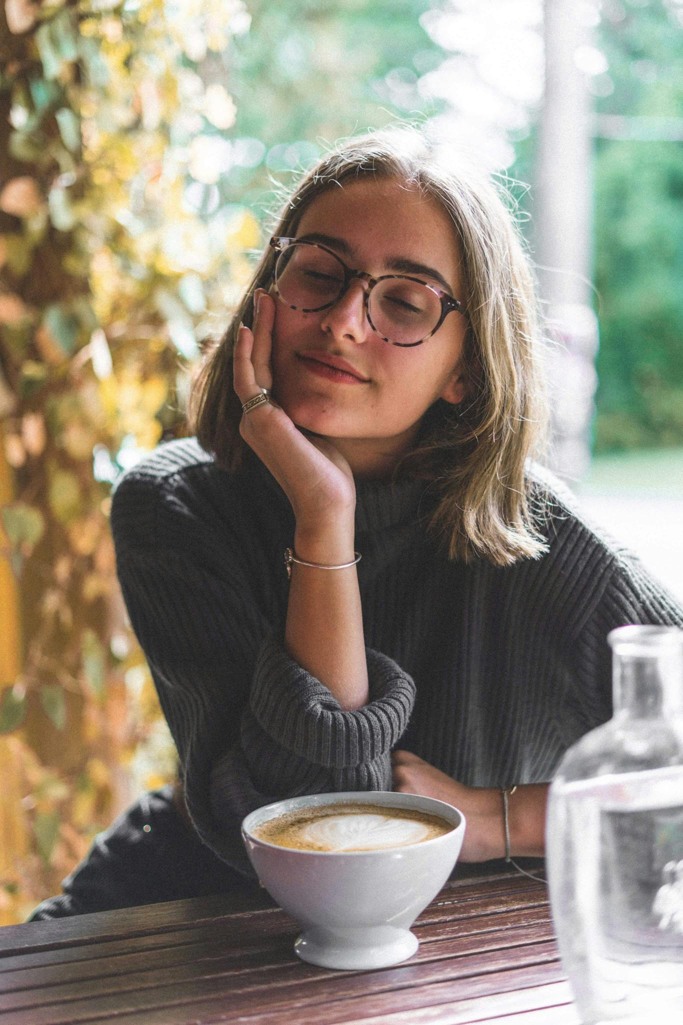Young woman relaxing with coffee outdoors, feeling calm and content.